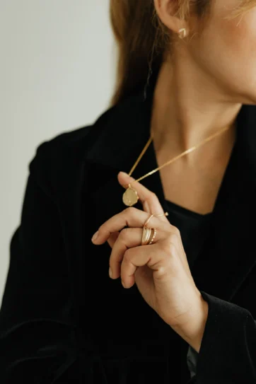 A woman wearing gold jewelry and rings.